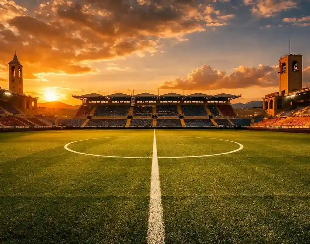 Campo da calcio italiano con linee bianche e tribuna sullo sfondo al tramonto